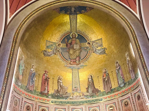 Photo showing the apse in St Francis Church, Cork. The photo depicts Christ in Majesty seated holding a book in one hand and his other hand raised. Two angels are on either side and eight saints stand below him. 