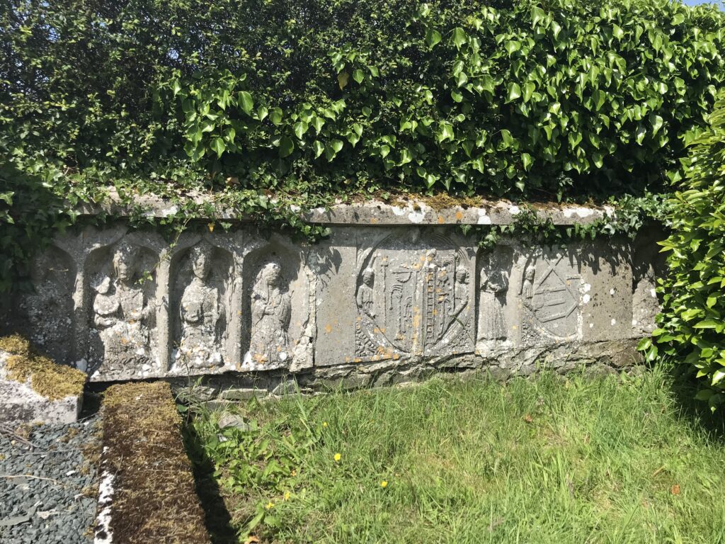 Tomb chest with saints, Kilcullen Franciscan friary. From left to right: figures of Saint Catherine of Alexandria, the Virgin and Child, Saint Margaret of Antioch and Saint Brigid (?), Saint Francis flanked by two rondels, one showing the Instruments of the Passion and the other, probably the arms of the FitzEustace and Janico families