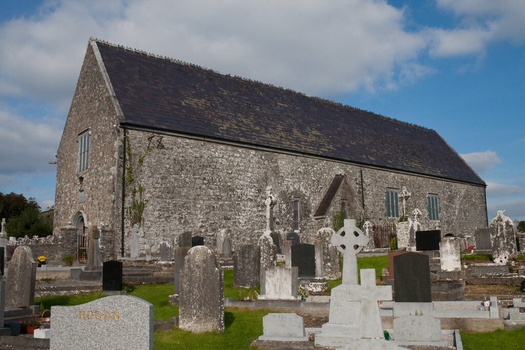 Exterior of Meelick Franciscan Friary with gravestones in front of the building.