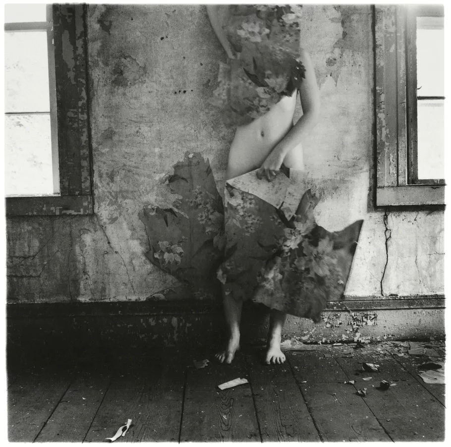 Black and white photograph by Francesca Woodman of nude person covering head and lower body with wallpaper. Self-portrait.