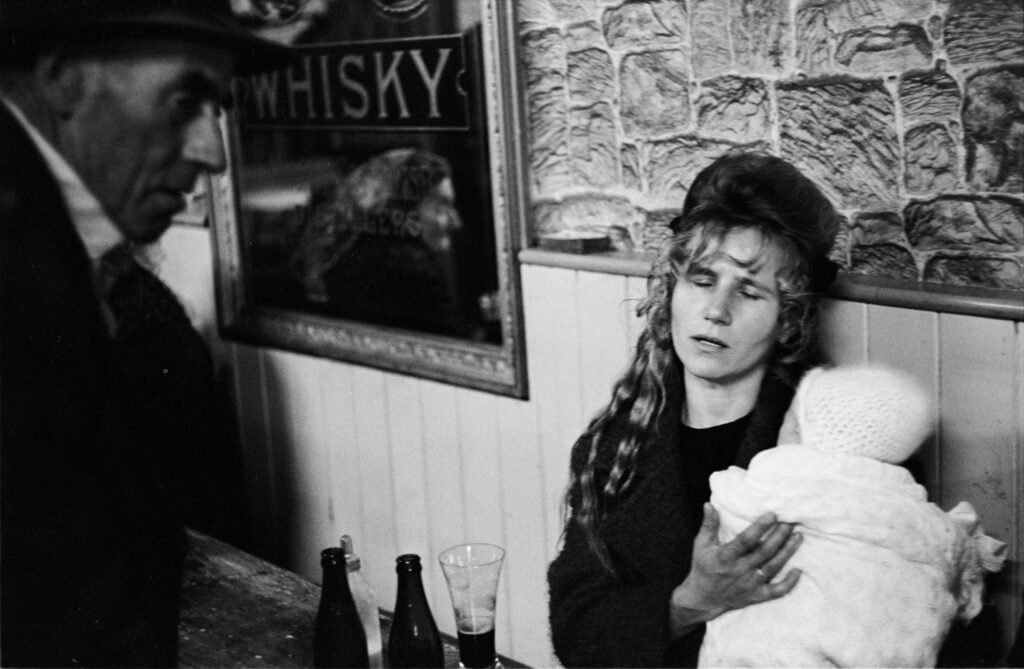 Black and white photo by Alen MacWeeney of singer Kitty Cassidy holding a baby and singing.