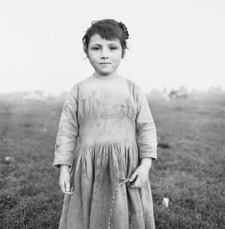 Black and white photo by Alen MacWeeney of girl standing in field.