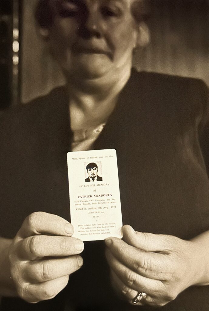 woman holding a funeral card, presumably of her son.