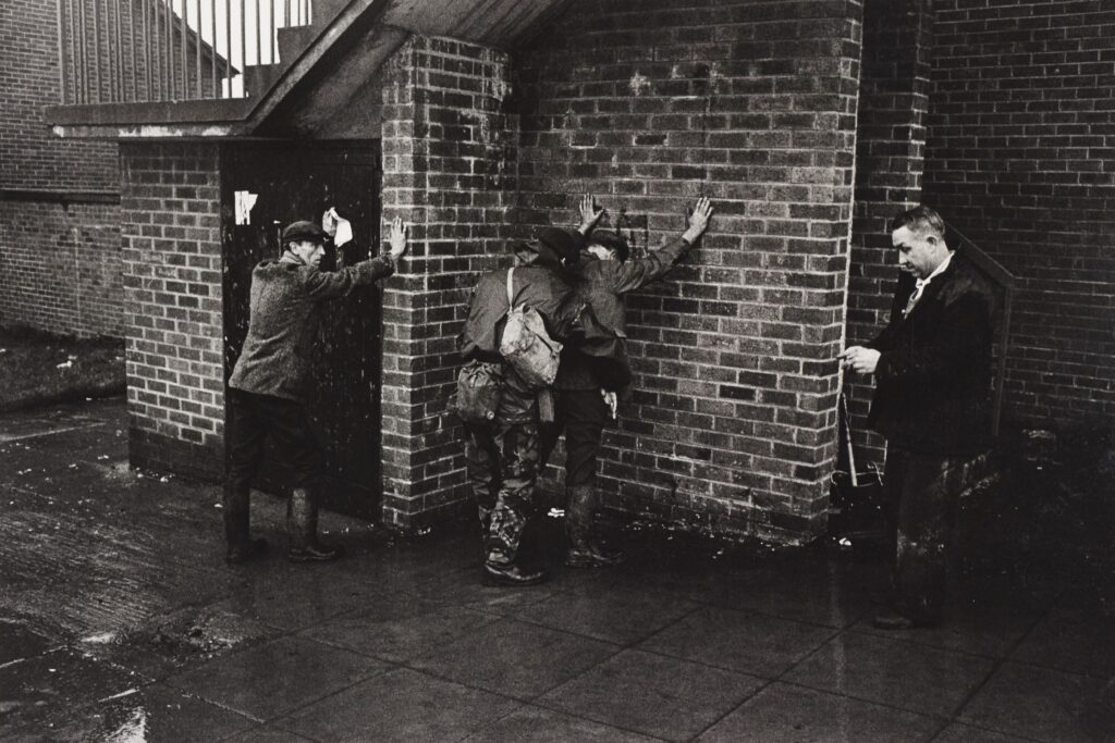 Stop-and-search by British soldiers. two men with their hands up against a wall.