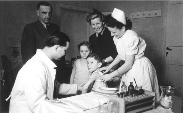 Nurses and doctors gathered around a child sitting on a exame table.