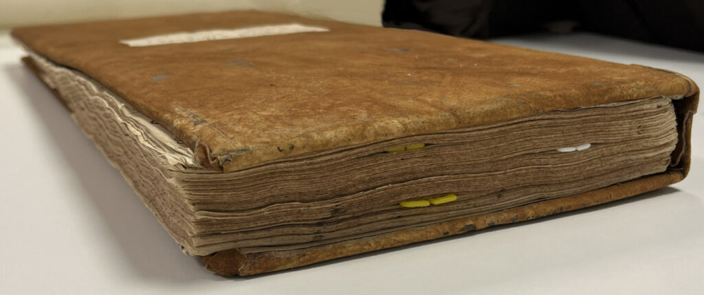 Detailed view of ledger, showing pages protruding from the boards.