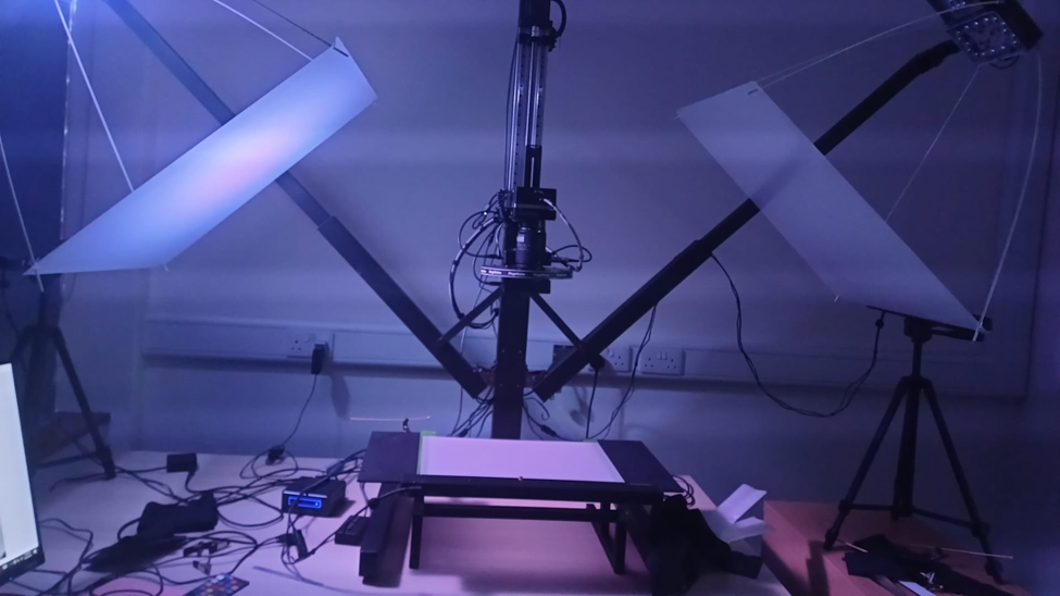 On the right and left are lights and in the middle is a table top for placing manuscripts. Behind is a pole to place the camera on. The camera can be raised or lowered.